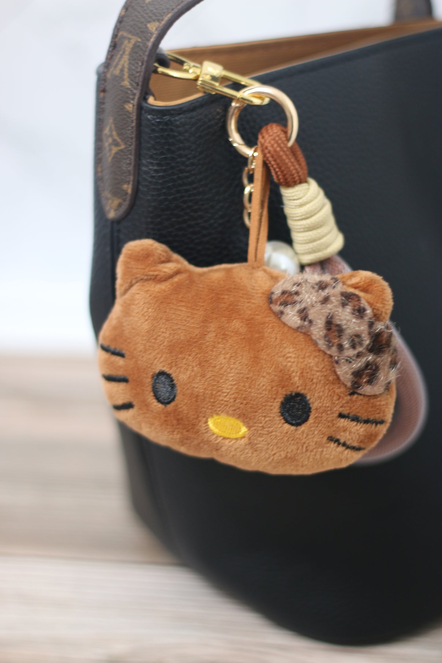 Plush cat keychain attached to a black designer handbag.