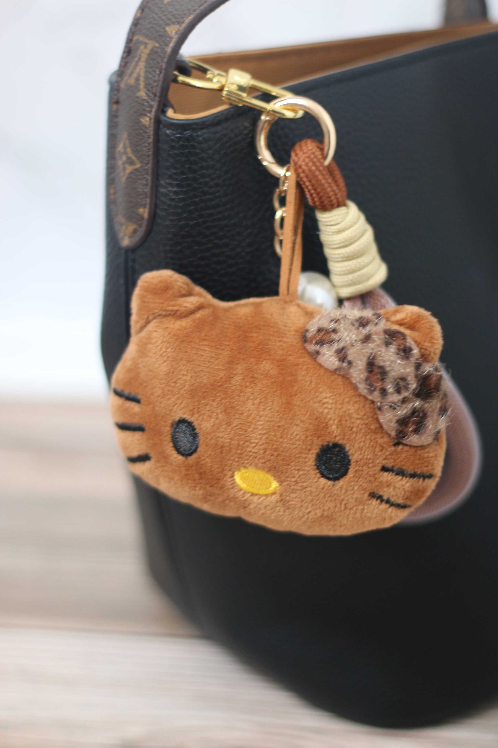 Plush cat keychain attached to a black designer handbag.